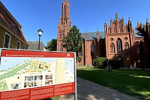 Nahaufnahme der Klosterkirche Malchow mit Informationsschild zum Klostergelände, Backsteinfassade und neugotischer Turm der Kirche